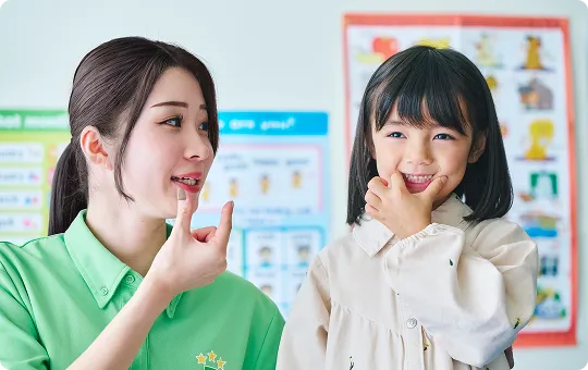 発音の練習をしている女の子と講師の写真