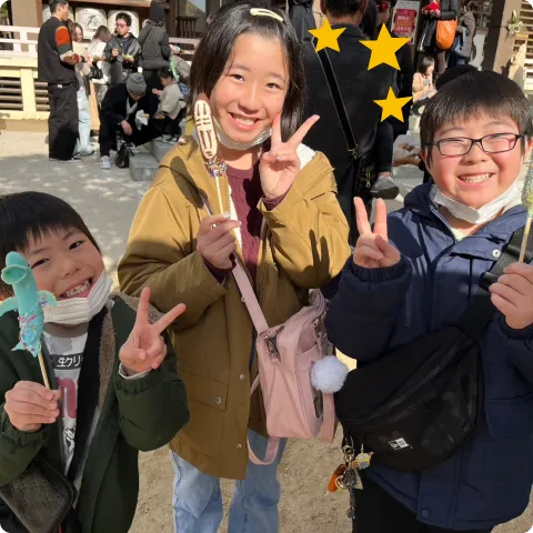 笑顔でピースしている隅田さんと子どもたちの写真