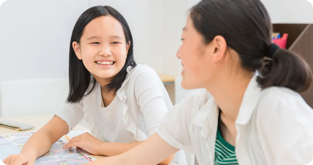 女の子二人が笑顔で勉強している写真