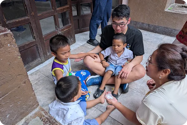 屋外で外国人講師と子どもたちが輪になって座りコミュニケーションを取っている写真