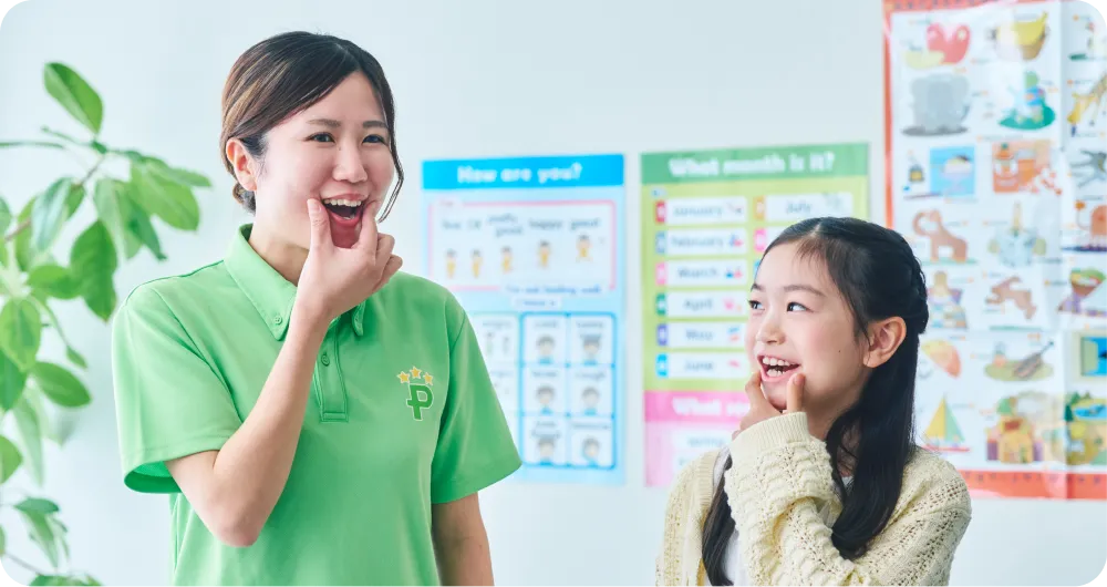 指を使って発音練習をする女の子と講師の写真