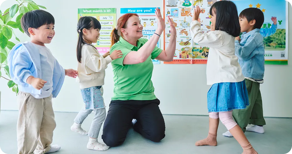 外国人講師とハイタッチをする子どもたちの写真