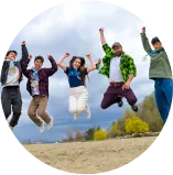 笑顔でジャンプしてる外国人講師と子どもたちの写真