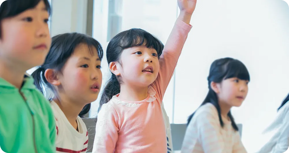 レッスンを受けている子どもたちと手をあげている女の子の写真