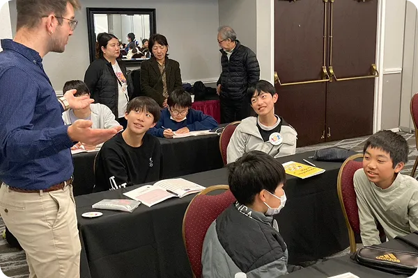 外国人講師のレッスンを座って聞いている男の子たちの写真