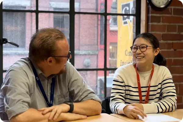 座りながら外国人講師と笑顔で会話をする女の子の写真