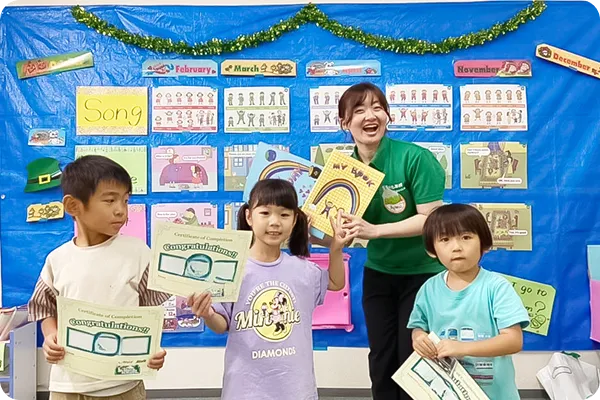 講師と子どもたちが認定証や修了証を持って笑顔で記念撮影をしている写真