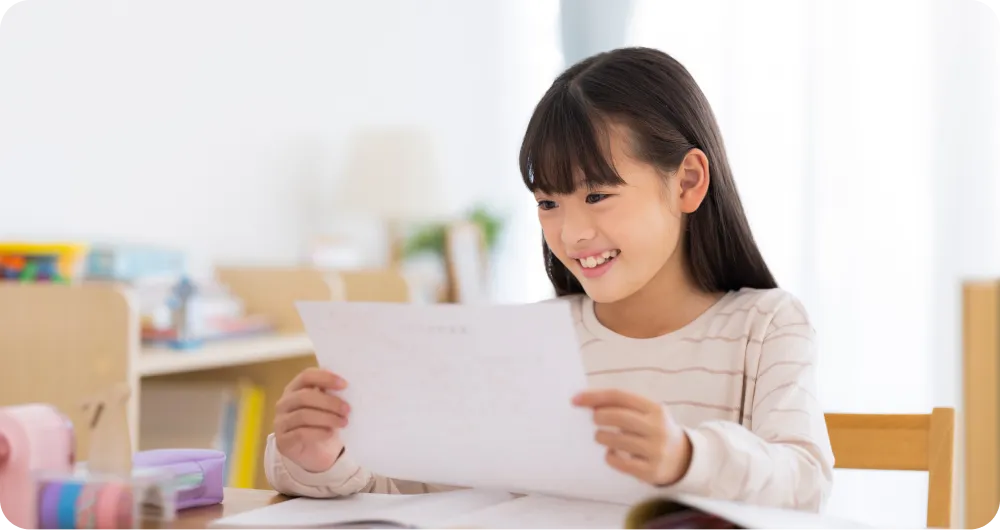 レポートカードを見て喜んでいる女の子の写真